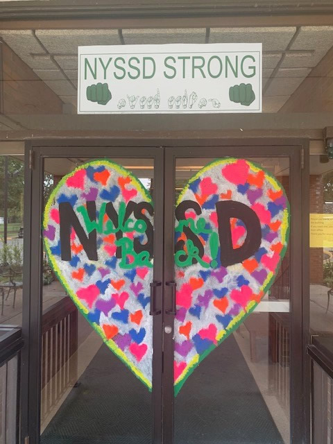 Glass door with sign saying "NYSSD Strong" and a heart