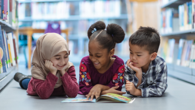 diverse students reading together on library floor