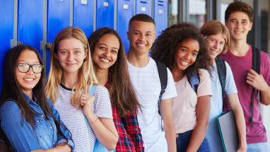 group of teenage students standing in front of lockers at school