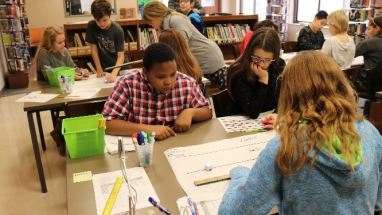 Nancy Claxton and Andrew Schmidle work with students in the library.